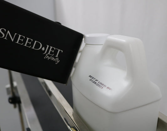 SNEEDJET Infinity industrial inkjet printer mounted at an angle next to a bottled juice container