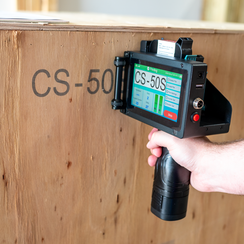 SNEED-JET® Freedom 21 Handheld Printer marking large text on a wooden shipping crate.