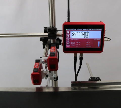 Front view of SNEED-JET Titan touchscreen controller with dual print heads positioned over a conveyor surface