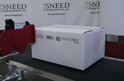 SNEED-JET Titan printing a barcode and QR code on a corrugated box moving along a conveyor line